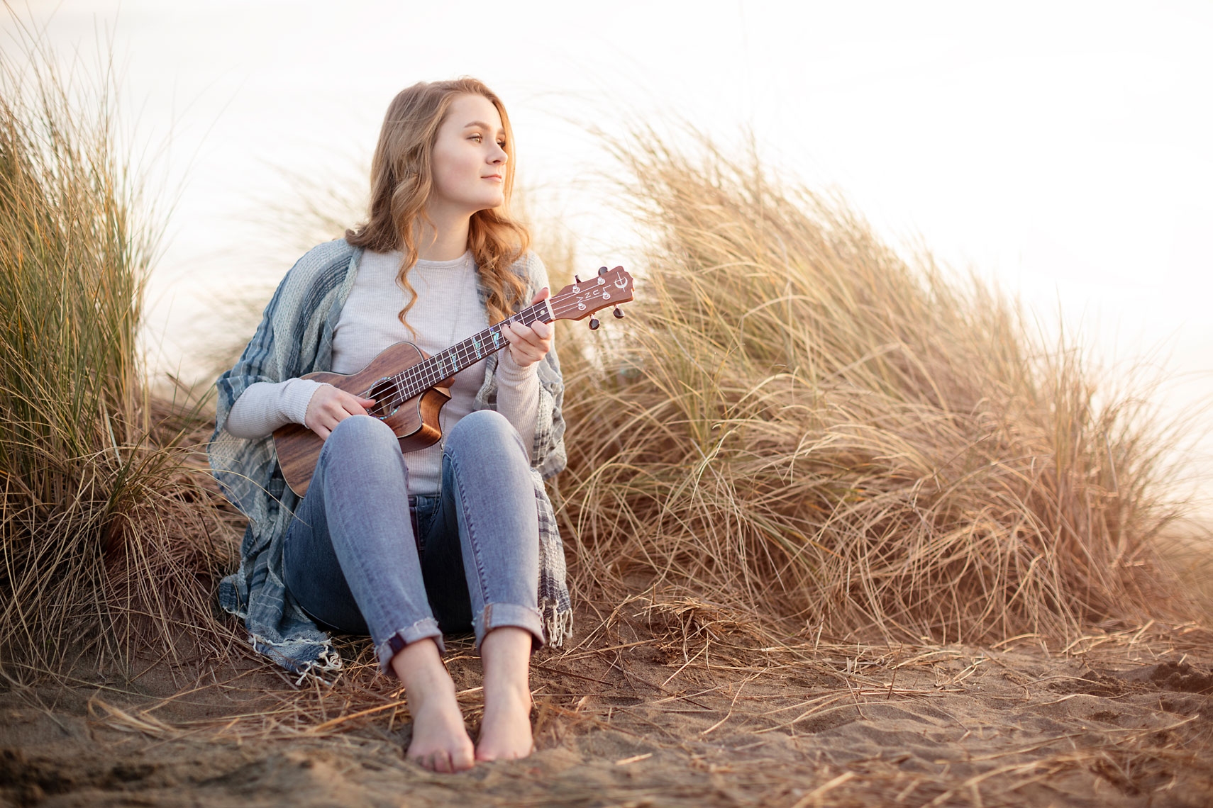 Teen girl playing ukulele in dunes